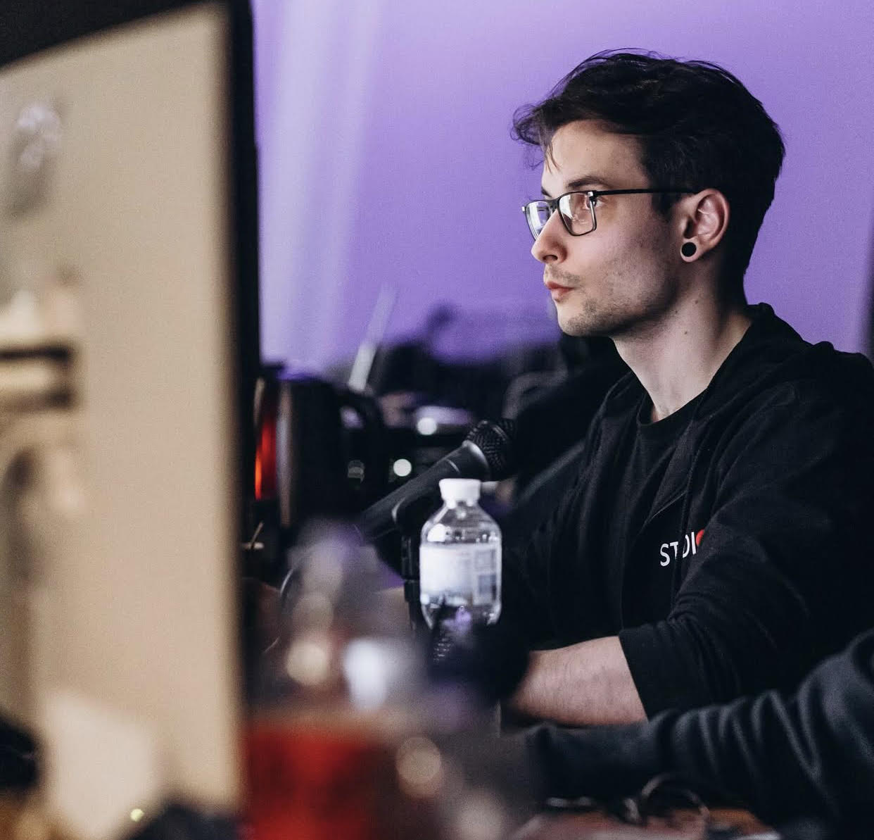 November Kendricks, Studio Manager and Set Director at Studio 7, seated at a multi-screen workstation, actively engaged in post-production and project oversight.